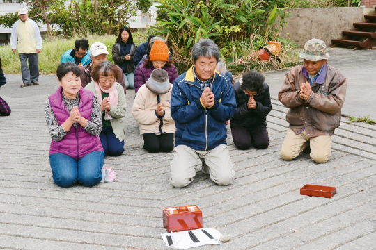 伝統行事「シマカンカー」で手を合わせ祈る地域住民