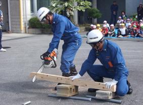 二人の消防団員が木材を切っている様子