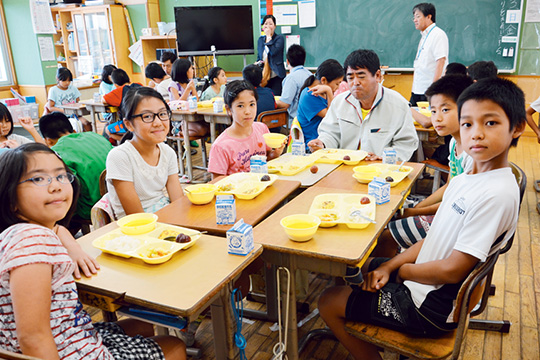 生産農家の島袋さんと給食を食べる北美小の生徒たち