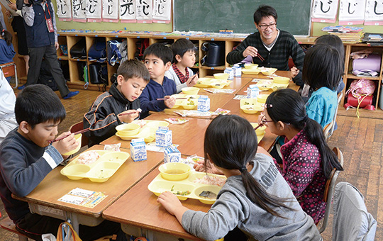 食用菊の入った給食を楽しむ山城さんとこども達